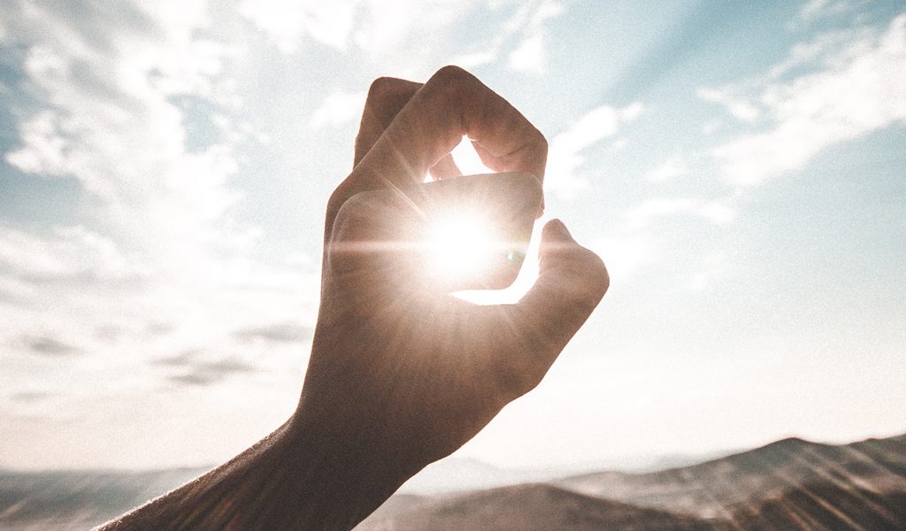 Notre Vision - Main formant un geste symbolique avec le soleil